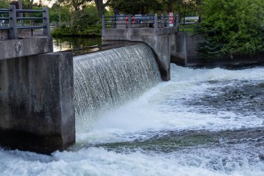 Kanada, Smiths Şelalesi 'ndeki beton bir barajın üzerinden çağlayarak akan su. Rideau Nehri 'nde güvenlik korkuluğu olan beton bir Weir. Kamu parkındaki rezervuar barajının manzarası