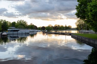 Smiths Falls, Kanada - 25 Mayıs 2025: rıhtımlı teknelerle nehrin üzerinde gün batımı. Le Boat kruvazörleri kanal rıhtımında..