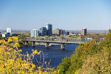 Kanada 'da sonbaharda Ottawa Nehri üzerindeki Ulusal Başkent ile Gatineau arasındaki köprü. Binalarla gökyüzü çizgisi