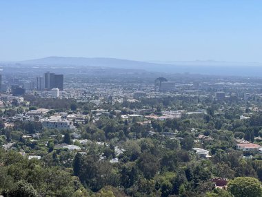 Yüksek bir bakış açısından geniş şehir, parlak mavi bir gökyüzünün altında açılır. Yeşil ağaçlar ve modern binalar uyum içinde harmanlanarak şehir yaşamının yanında doğayı da sergiliyorlar..