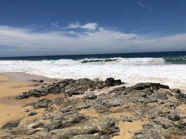 Dalgalar engebeli bir sahile yuvarlanarak sakin bir atmosfer yaratıyor. Güneşli bir günde doğanın güzelliğini yakalayan çarpıcı bir sahil manzarası dinlenmeyi ve yansımayı davet eder..