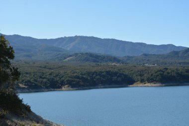 Parlak güneş, yemyeşil tepeler ve uzak dağlarla çevrili sakin gölün üzerinde parlıyor. Bu da doğa aşıkları ve maceracılar için mükemmel bir açık hava kaçışı yaratıyor..