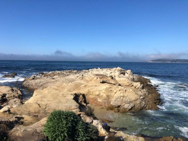 Yumuşak dalgalar, büyük ve yıpranmış kayaların üzerinde dinlendirici bir melodi yaratır. Güneş doğuyor, gökyüzünü maviye boyuyor kıyı şeridi boyunca sakin titreşimlerle..