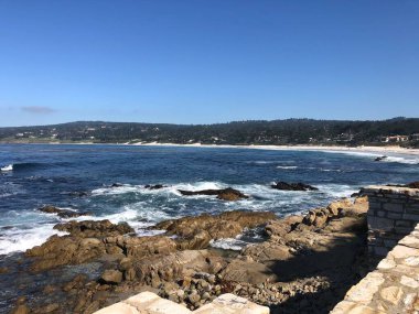Dalgalar engebeli kayalara çarparken, parlak güneş okyanusun üzerinde parlıyor. Kıyı şeridinin çarpıcı güzelliğini ortaya çıkarıyor. Yumuşak kum, kıyı boyunca ziyaretçileri bekliyor. Rahatlamaya davet ediyor..