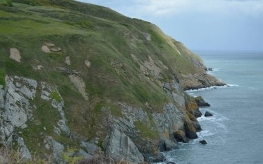 Dalgaların engebeli kayalara çarptığı okyanustan yükselen sarp ve yeşil uçurumların çarpıcı manzarası gri gökyüzünün altında doğanın güzelliğini gözler önüne seriyor..
