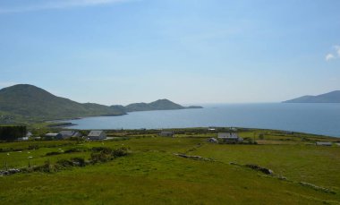 Uçsuz bucaksız yeşil tarlalar berrak sulara doğru uzanıyor, uzakta yumuşak tepeler yükseliyor. Küçük beyaz evler manzarayı noktalıyor. Huzurlu ve davetkar bir ortam yaratıyor..