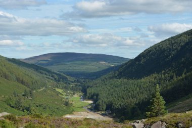 Huzurlu bir sahnede İrlanda 'nın görkemli dağları arasında uzanan engin yeşil bir vadi sergileniyor..