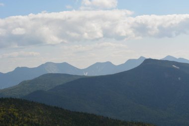 Olağanüstü sıradağlar ufuk boyunca uzanır, zirvelerine ışık bulutları dokunur. Bereketli yeşillik ve nefes kesici manzaralarla dolu sakin bir manzara keşfi davet ediyor..