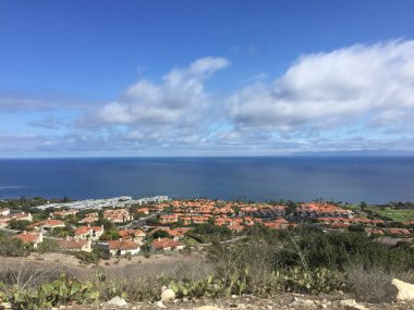 Bir tepeden çarpıcı bir manzara kıyı şeridini çevreleyen renkli evleri yakalıyor. Aşağıda, ışıl ışıl okyanus uzanıyor, ılık, güneşli bir gökyüzü tarafından kabarık bulutlarla kucaklanıyor..