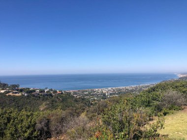 Güzel bir bakış açısı, engin okyanusu ve açık mavi gökyüzünün altında uzanan bir kıyı şeridini gözler önüne seriyor. Bereketli yamaçlar huzur dolu manzaraya ekleniyor. Rahatlama ve keşifleri davet ediyor..