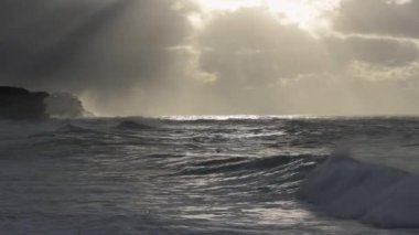 Bronte Beach Sydney 'deki fırtınalı gündoğumu sırasında ekranda kürek çeken tanınmayan yalnız sörfçü.