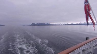 Norveç 'in sakin kutup sularında yelken açmak. Kıç tarafındaki POV dalgalanan bayrak gösteriyor
