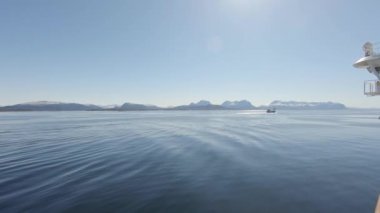 Daha büyük bir gemi Norveç 'in sakin denizinde seyrediyor. İskele tarafında daha küçük bir gemi ve dağlar kadar mesafe var.