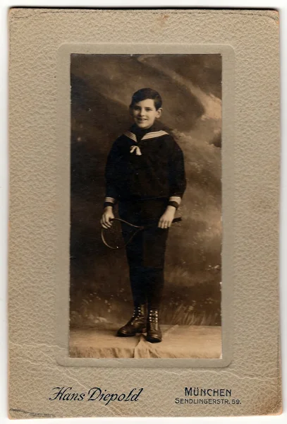 Vintage kabiny karta ukazuje mladý chlapec nosí kostým námořník a drží tenisovou raketu. — Stock fotografie