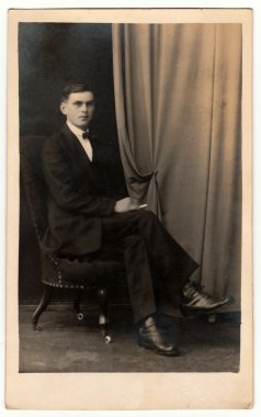 Vintage fotoğraf genç adam koltukta oturur gösterir. Antika siyah ve beyaz stüdyo portresi.