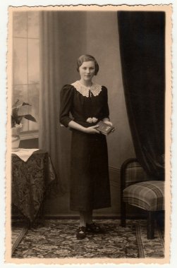Vintage fotoğraf kitap ile zarif bir kadın bir fotoğraf stüdyosunda poz gösterir. Koyu sepya tonu ile fotoğraf. Siyah ve beyaz stüdyo portresi.