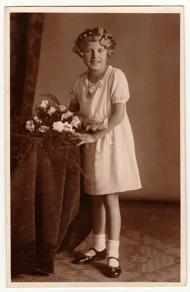 Foto vintage mostra jovem com poses de buquê em um estúdio de fotografia. Foto com tom sépia escuro. Retrato de estúdio preto e branco . — Fotografia de Stock