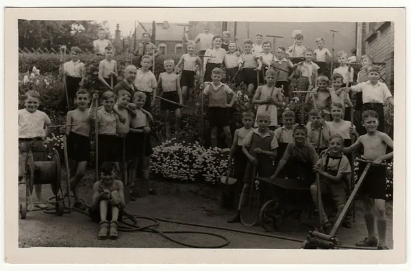 Fotografie vintage arată băieții cu instrumente de grădinărit pozează în aer liber. Fotografie antică alb-negru . — Fotografie, imagine de stoc