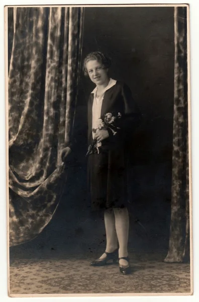 Vintage photo shows woman with a bunch of flowers, poses in a photography studio. Photo with dark sepia tint. Black & white studio portrait. — Stock Photo, Image