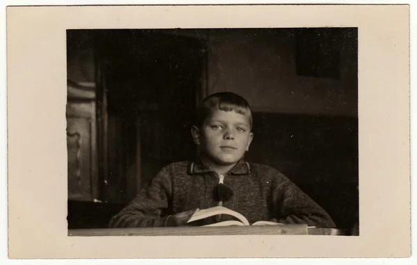 ヴィンテージ写真は、机の上に本を持つ生徒の少年を示しています。黒と白のレトロな写真. — ストック写真