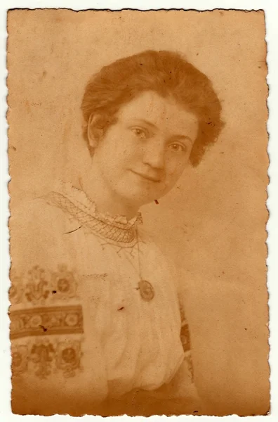 Vintage photo shows young woman wears a folk blouse with floral pattern (Sunday best dress). Antique black & white studio portrait. — Stock Photo, Image