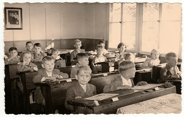 Retro photo shows pupils sit at the wooden school desks in the classroom. — Stock Photo, Image