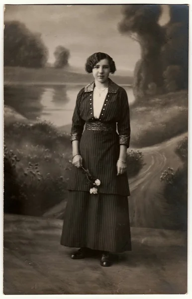 Vintage photo shows woman holds white roses. Photo with dark sepia tint. Black & white studio portrait. — Stock Photo, Image