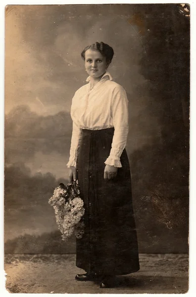 Vintage photo shows woman holds a bunch of lilac. Black & white photo with sepia tint. — Stock Photo, Image