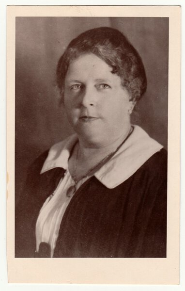 Vintage photo shows a mature woman poses in a photography studio. Black & white studio portrait.