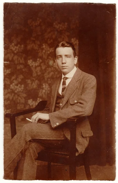 Foto vintage muestra al hombre sentado en la silla. Retrato de estudio en blanco y negro con tinte sepia —  Fotos de Stock
