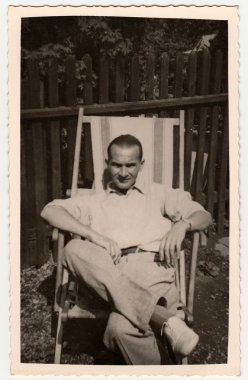 Çekoslovakya Sosyalist Cumhuriyeti - 1950'lerde yaklaşık: Bahçedeki ahşap/Tekstil şezlong Vintage fotoğraf gösterileri adam oturur. Siyah ve beyaz fotoğraf.