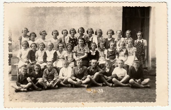 Foto vintage muestra un grupo de compañeros de escuela y profesora. Foto en blanco y negro . —  Fotos de Stock