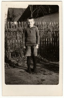 Vintage fotoğraf genç çocuk (öğrenci, öğrenci) ahşap çit önünde duruyor gösterir. Siyah ve beyaz antika fotoğraf.