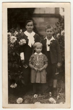 Vintage fotoğraf çocuklu genç kadın gösterir (erkek ve kız) bahçede poz. Siyah ve beyaz antika fotoğraf.