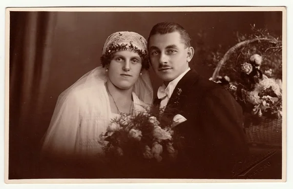 Vintage photo of newlyweds. Bride wears a veil and holds wedding bouquet. Black & white antique studio portrait. — Stock Photo, Image