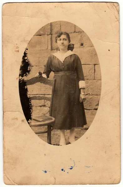 Na fotce se žena staví vedle historického křesla. Starodávná černá & bílá fotografie je oválný tvar. — Stock fotografie