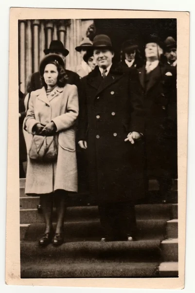 Vintage photo shows newlyweds stand on stairs after wedding ceremony. Black & white antique photography.