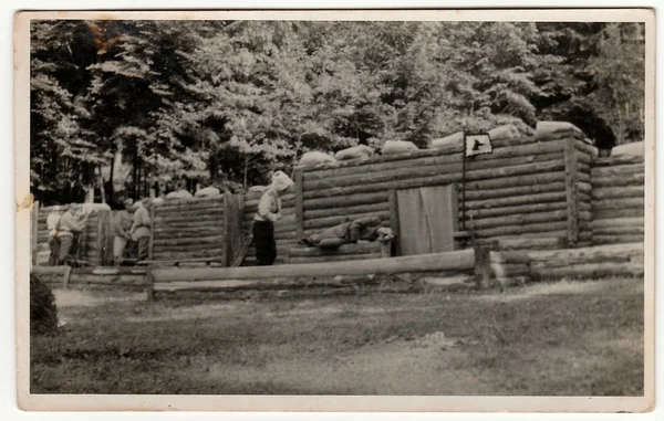 Vintage photo shows soldiers in front of log fortification. Black & white antique photography. — Stock Photo, Image