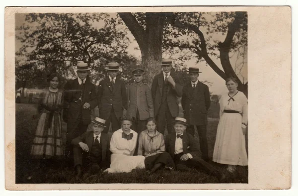 Fotografia de epocă arată că tinerii pozează în aer liber. Bărbații poartă o pălărie cu bandă largă și costum întunecat. Fotografie antică alb-negru . — Fotografie, imagine de stoc