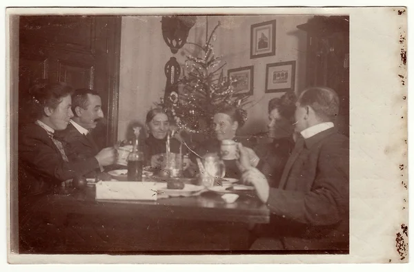 Photo vintage montrant la famille assise à la table pendant la période de Noël. Dans la chambre est un arbre de Noël . — Photo