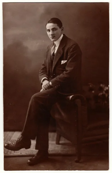 Vintage fotó mutatja a fiatalember visel öltönyt, és ül a kanapén. Fotózás a szépia hatás. — Stock Fotó