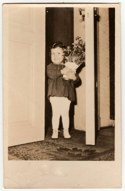 Vintage fotoğraf sevimli küçük bir kız çiçeklerle vazo tutar gösterir. Retro fotoğrafçılık.