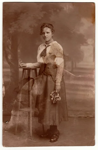 La foto de la vendimia muestra a una joven sosteniendo rosas. Fotografía de estudio con efecto sepia . — Foto de Stock