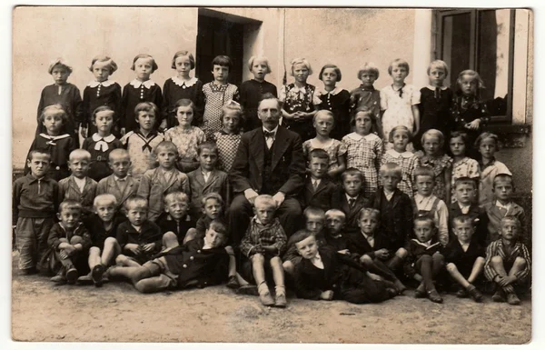 Foto de la vendimia muestra a los alumnos (compañeros de escuela) y su profesor posan frente a la escuela. Fotografía antigua en blanco y negro . — Foto de Stock