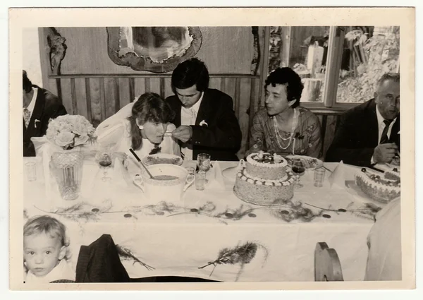 Retro zdjęcie pokazuje ludzi podczas święta ślubu. Groom karmi narzeczonej. Czarny & biały zabytkowe Fotografia. — Zdjęcie stockowe
