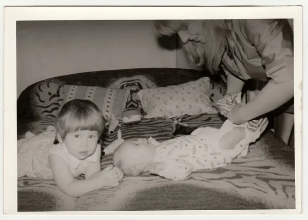 Ретро-фото показывает, как мама надевает ребенка. Черно-белая винтажная фотография . — стоковое фото