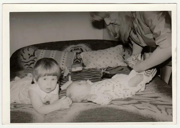 Foto retrô mostra mãe coloca sobre o bebê. Preto & branco vintage fotografia . — Fotografia de Stock