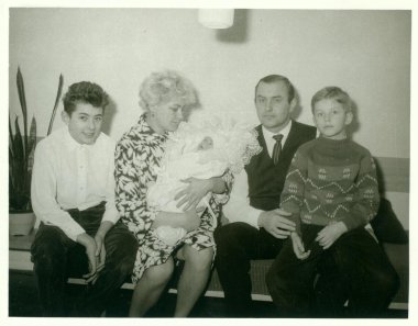 Retro fotoğraf aile oturur oturma odasında gösterir. Kadın masa üstü şarj aletler yeni doğmuş bebek. Vintage siyah ve beyaz fotoğraf.