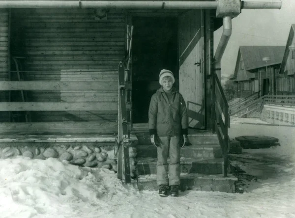Retro fotoğraf genç bir çocuk kış döneminde gösterir. Çocuk kayakları ile dağ evi önünde duruyor. Vintage siyah ve beyaz fotoğraf. — Stok fotoğraf