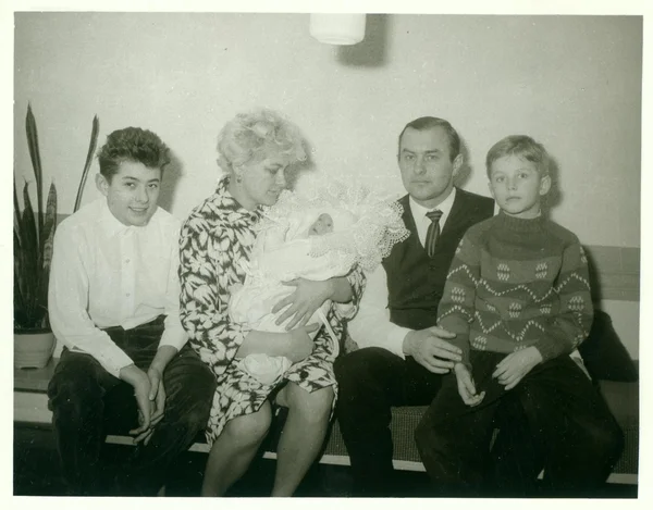 Foto retro muestra la familia se sienta en la sala de estar. Mujer acuna bebé recién nacido. Vintage fotografía en blanco y negro . — Foto de Stock